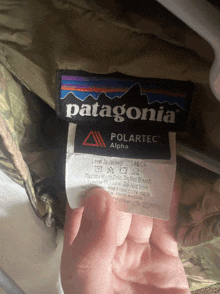 someone is holding a patagonia polartec alpha label