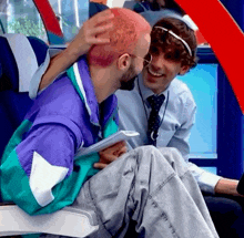 a man in a purple jacket is petting another man with pink hair