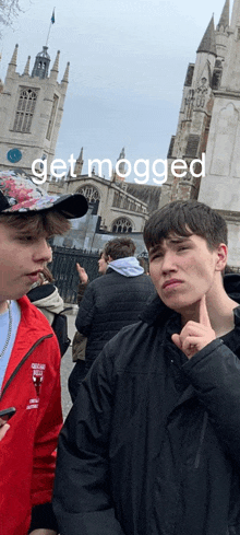 two young men are standing in front of a building with the words get mogged written on the bottom