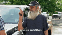 a man with a beard and glasses is standing in front of a truck and pointing at the camera .