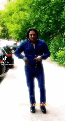 a man in a blue shirt is dancing on a sidewalk