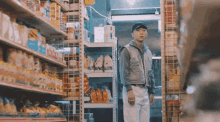 a man in a vest stands in a grocery store aisle looking at a shelf with a bag of rice on it