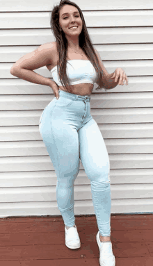 a woman in a white crop top and light blue jeans