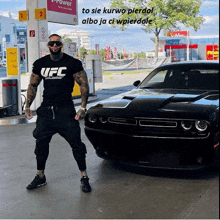 a man wearing a ufc shirt is standing in front of a car