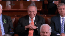 a man in a suit and tie is smiling while sitting in a row of men in suits and ties