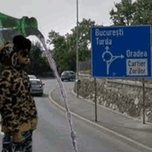 a person is pouring a drink from a bottle on the side of a road .