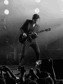 a man in a suit is playing a guitar on a stage