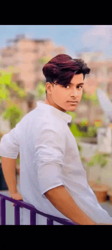 a young man in a white shirt is leaning against a railing .