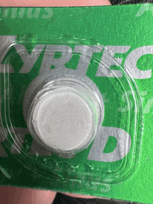 a green and white packaging with a white button on it