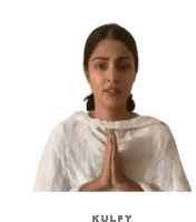 a woman in a white dress is praying with her hands folded in prayer .