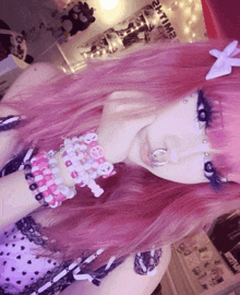 a girl with pink hair is wearing a lot of bracelets and a sign that says smiling in the background