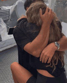 a man wearing a watch is hugging a woman in a black shirt