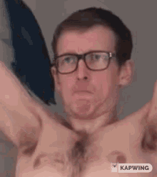 a shirtless man wearing glasses is making a funny face while holding a pillow .