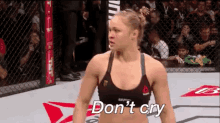 a woman is standing in a boxing ring with the words `` don 't cry '' written on the floor .