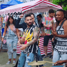 a group of people are dancing in front of a tent with a man wearing a shirt that says i love ebrada