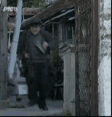 a man wearing a hat is walking down a sidewalk in front of a building with a sign that says pyc