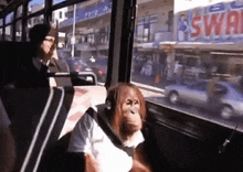 an orangutan wearing headphones is sitting on a bus in front of a store that says swol