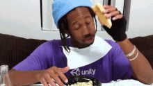 a man wearing a purple shirt that says unity is eating food