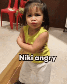 a little girl with her arms crossed and the words " niki angry " on the bottom