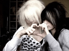 two girls making a heart shape with their hands .