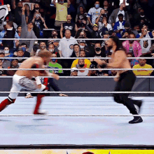 two men are wrestling in front of a crowd with one wearing a shirt that says ' chicago cubs '