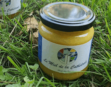 a jar of le miel de la cathedrale sits on the grass