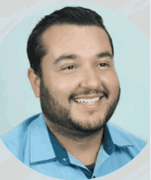 a man with a beard wearing a blue shirt smiles for the camera