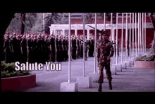 a soldier is walking in front of a row of flags with the words salute you written above him .