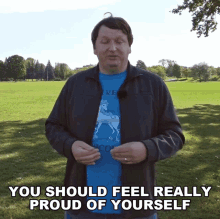 a man wearing a t-shirt that says " you should feel really proud of yourself " stands in a park