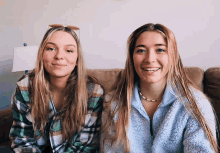 two girls are sitting next to each other on a couch and smiling for the camera