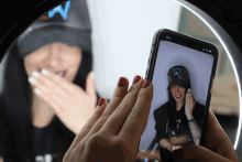 a person taking a picture of a woman wearing a black hat