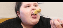 a very fat woman is eating a banana with a fork .