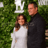 a man and a woman are posing for a picture on a red carpet in front of a tv awards sign