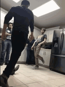 a man wearing a t-shirt that says heavy metal is standing in a kitchen with other men