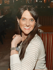 a woman wearing a smart watch is smiling for the camera