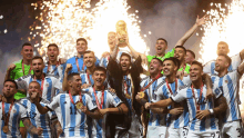 a group of soccer players are holding up a trophy with fireworks behind them