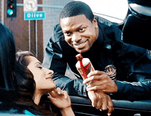 a man in a police uniform is giving a woman a coca cola can