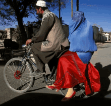 a man is riding a bike with a woman wearing a blue veil on the back