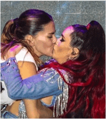 two women are kissing on a stage . one of the women has red hair .