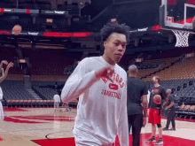 a man wearing a white shirt that says basketball on it is standing on a basketball court