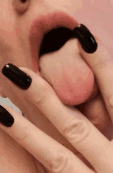 a woman with black nails is licking her lips