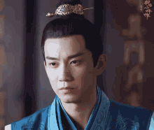 a man wearing a blue robe and a crown looks at the camera