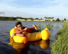 a man is laying on a yellow raft in a body of water with a sign in the background that says ' stadium '