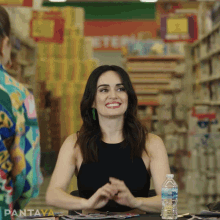 a woman sits at a table with a bottle of water in front of her and the word pantaya on the bottom