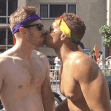 a shirtless man with a purple headband kissing another shirtless man