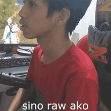 a young man in a red shirt sits in front of a computer screen with the words sino raw ako on the bottom right