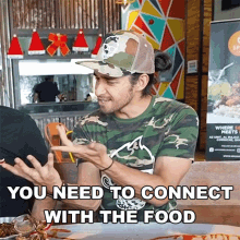 a man sitting at a table with a sign that says " you need to connect with the food " on it