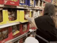 a woman in a black shirt is shopping in a grocery store and reaching for a bag of ruffles chips