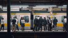 a group of people waiting for a train at a station with a sign that says ' tokyo ' on it