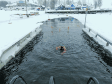 a man in a green hat is swimming in a frozen body of water